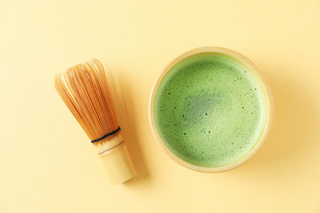 Refreshing green matcha in ceramic bowl and bamboo whiskey on yellow table, flat layの写真素材