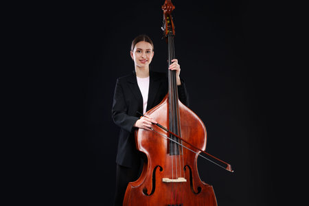 Girl with double bass and bow on black background