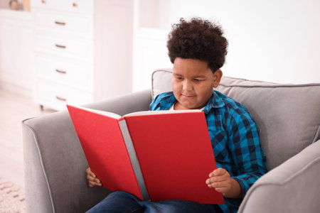 Boy reading book on sofa at homeの写真素材