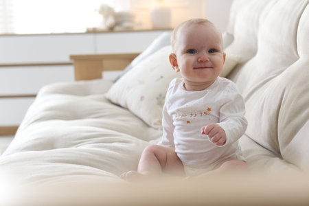 Cute little baby on sofa at home. Space for textの写真素材