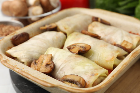 Delicious stuffed cabbage rolls with mushrooms in baking dish on table, closeupの写真素材