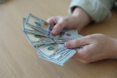 Man with dollar banknotes at wooden table, closeup