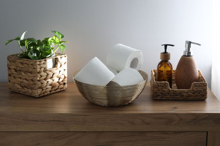 Toilet paper rolls in bowl, soap and houseplant on wooden table indoors