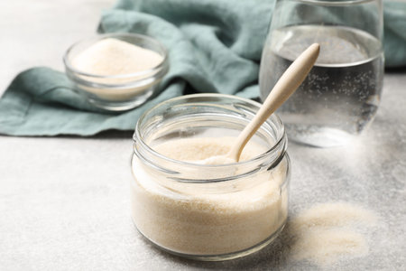 Gelatin powder and glass of water on light gray table, closeupの写真素材