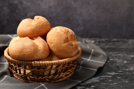 Fresh tasty buns and towel on black table, closeup. Space for text