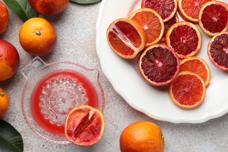 Ripe Sicilian oranges, squeezer and green leaves on gray table, flat layの写真素材