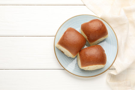 Fresh tasty buns on white wooden table, top view. Space for text