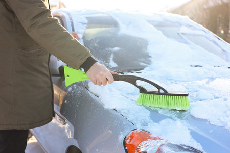 Man cleaning snow from car outdoors on winter day, closeup