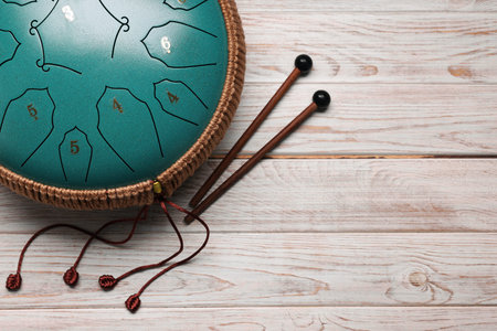 Steel tongue drum and mallets on wooden background, flat lay with space for text. Percussion musical...