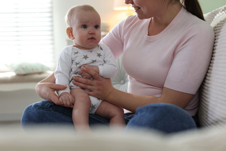Mother and her cute baby on sofa at home, closeup