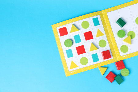 Geometrical puzzle pieces for children on light blue background, flat lay. Space for text