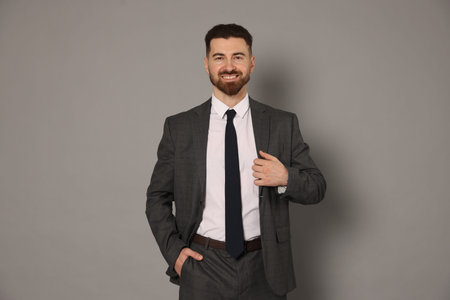 Portrait of smiling businessman in suit posing on gray background