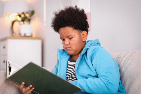 Boy reading book on sofa at homeの写真素材