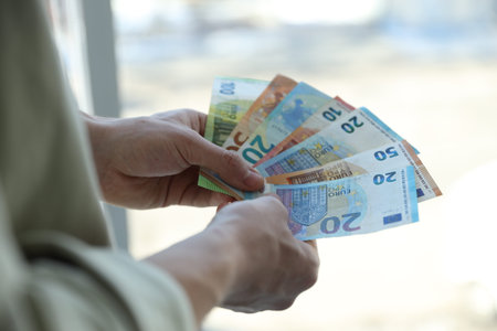 Man with euro banknotes against blurred background, closeup