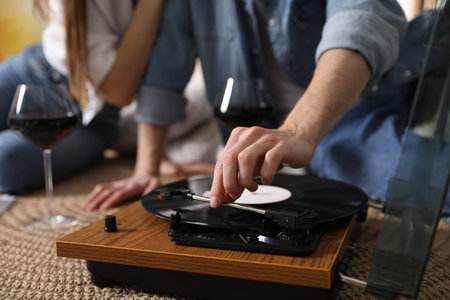 Romantic date. Couple listening to vinyl record on floor indoors, closeup