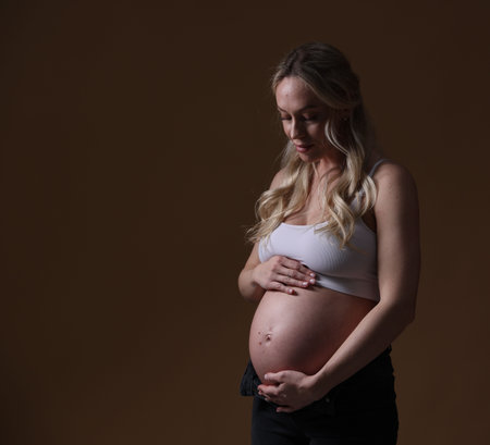 Beautiful pregnant woman on brown background. Space for text