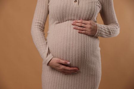 Beautiful pregnant woman on beige background, closeup