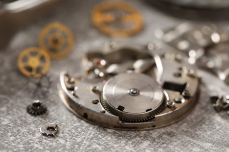 Mechanism of vintage wrist watch and gears on gray table, closeup