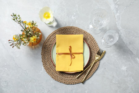 Stylish table setting with floral decor on gray marble background, flat lay
