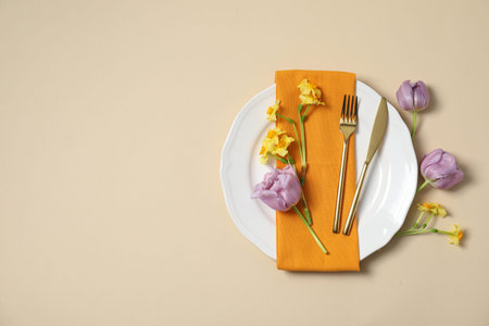 Beautiful table setting with floral decor on beige background, flat lay. Space for text