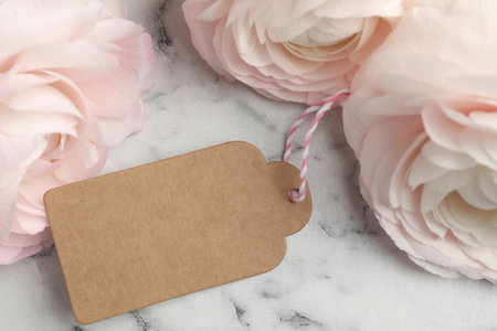 Beautiful flowers and blank card on white marble background, closeup. Mockup for design