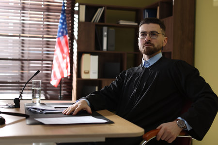 Judge in glasses sitting at table in office