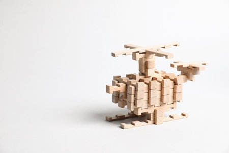 Helicopter made of wooden blocks on light background. Space for text