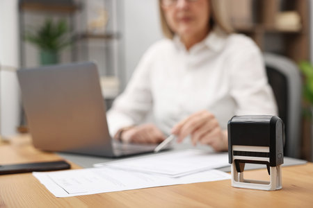 Notary working at wooden desk in office, focus on stamp