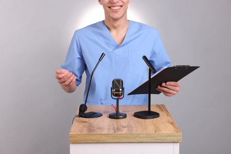 Doctor with clipboard giving interview on light gray background