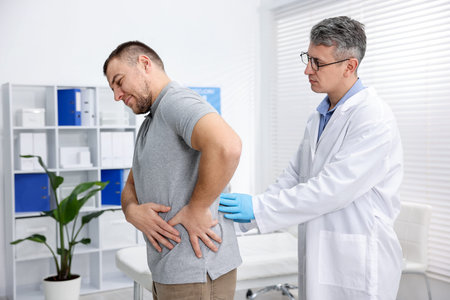 Urologist in medical coat and glasses examining patient in clinic