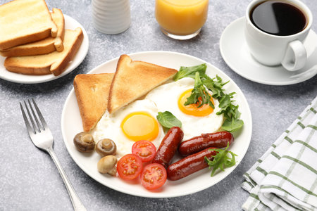 Delicious breakfast with fried eggs and sausages served on gray table, closeup