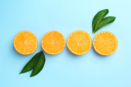 Fresh juicy tangerines and leaves on light blue background, flat lay