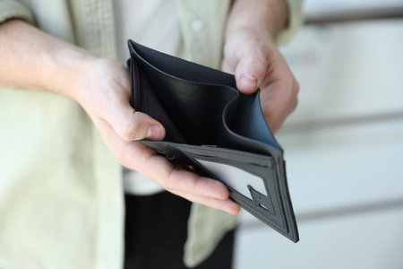Man with empty wallet against blurred background, closeup
