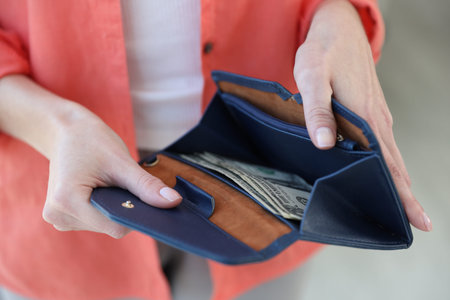 Woman holding wallet with dollar banknotes against blurred background, closeup
