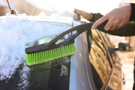 Man cleaning snow from car outdoors on winter day, closeup