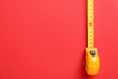 Measuring tape on red background, top view. Space for text