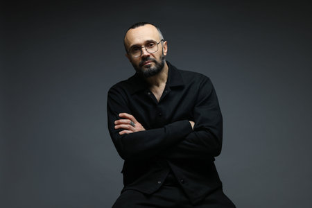 Fashion model. Handsome man in glasses on gray background