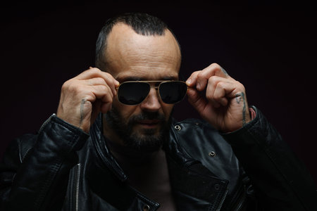 Fashion model. Handsome man in sunglasses on black background