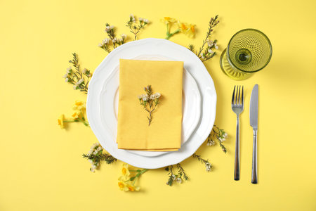 Beautiful table setting with floral decor on yellow background, flat lay