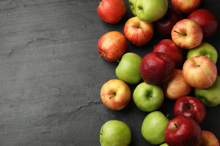 Fresh ripe apples on gray textured table, flat lay. Space for text