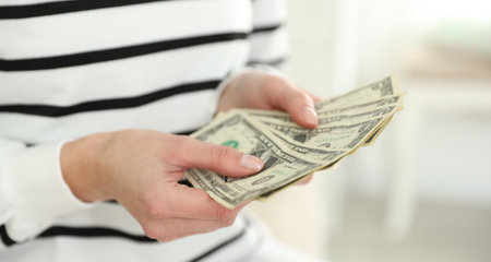 Woman counting dollar banknotes indoors, closeup viewの写真素材