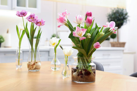 Beautiful spring flowers in vases on wooden table indoors, closeup