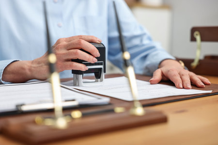 Notary stamping document at desk in office, closeup
