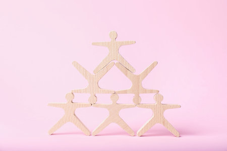 Wooden human shaped figures on pink backgroundの写真素材