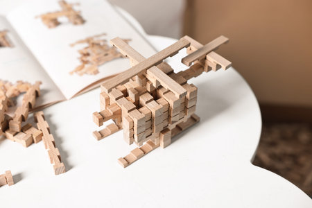 Helicopter figure made of wooden blocks on white table indoors, closeup