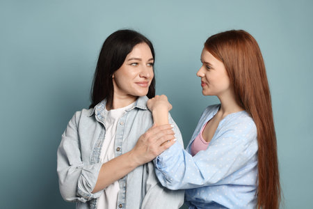 Mother and her teenage daughter on light blue background