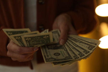 Woman counting dollar banknotes indoors, closeup view