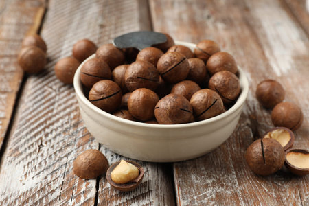Macadamia nuts in bowl on wooden table, closeupの写真素材
