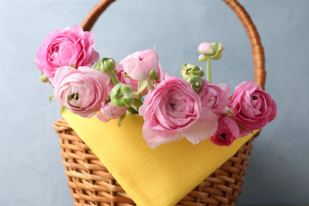 Beautiful flowers in wicker basket on grey background, closeup