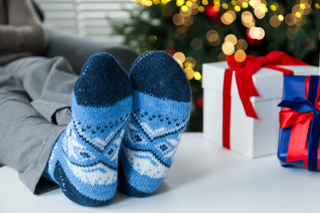 Woman wearing cozy socks and Christmas gifts at home, closeup